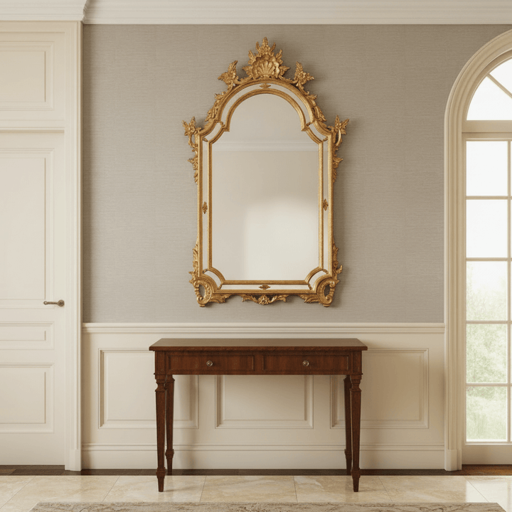 Italian Rococo Ornate Gold Wall Mirror on elegant wall above wooden table.