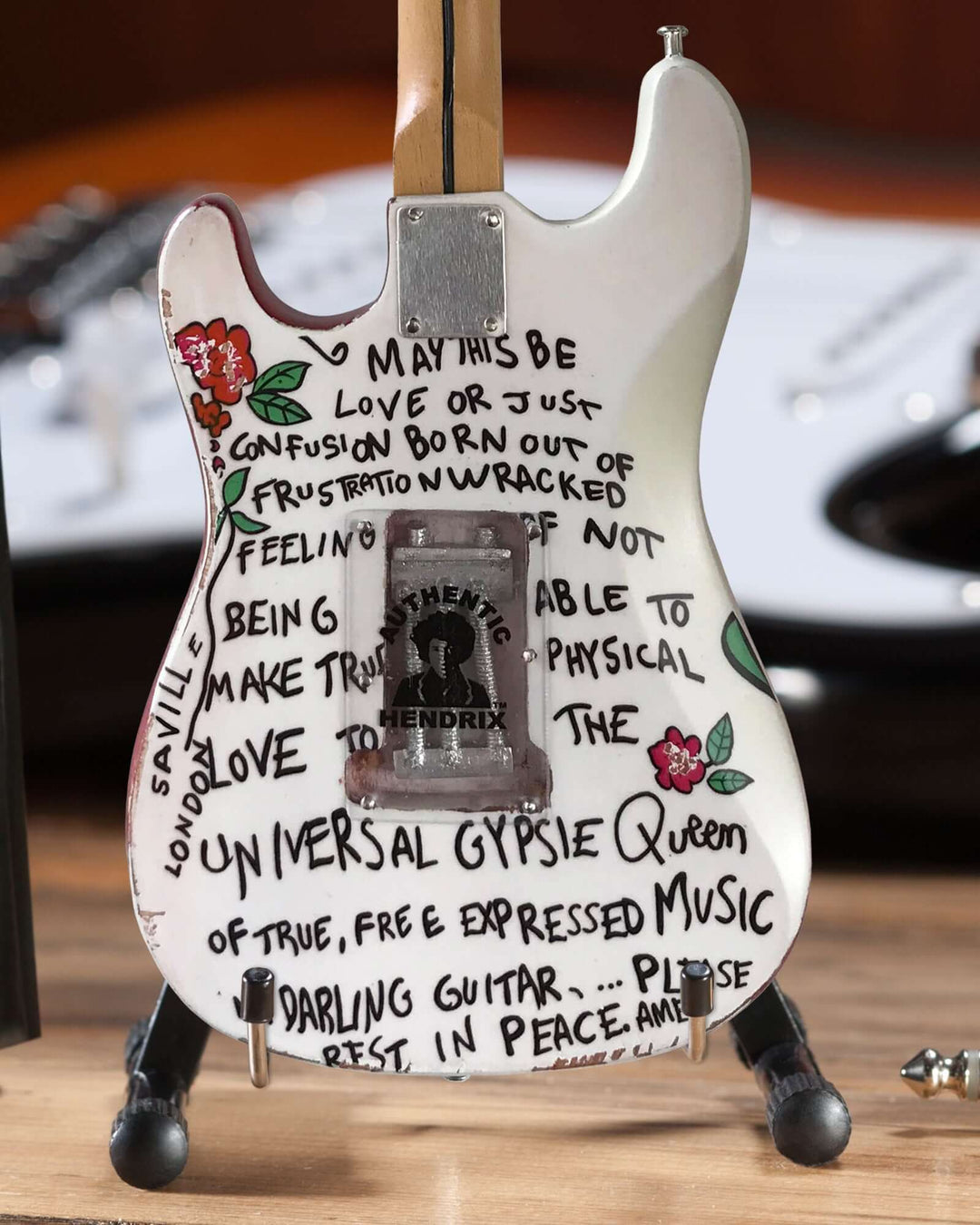 Jimi Hendrix Fender Stratocaster Mini Guitar Replica with artistic writings on the body, displayed on a stand.