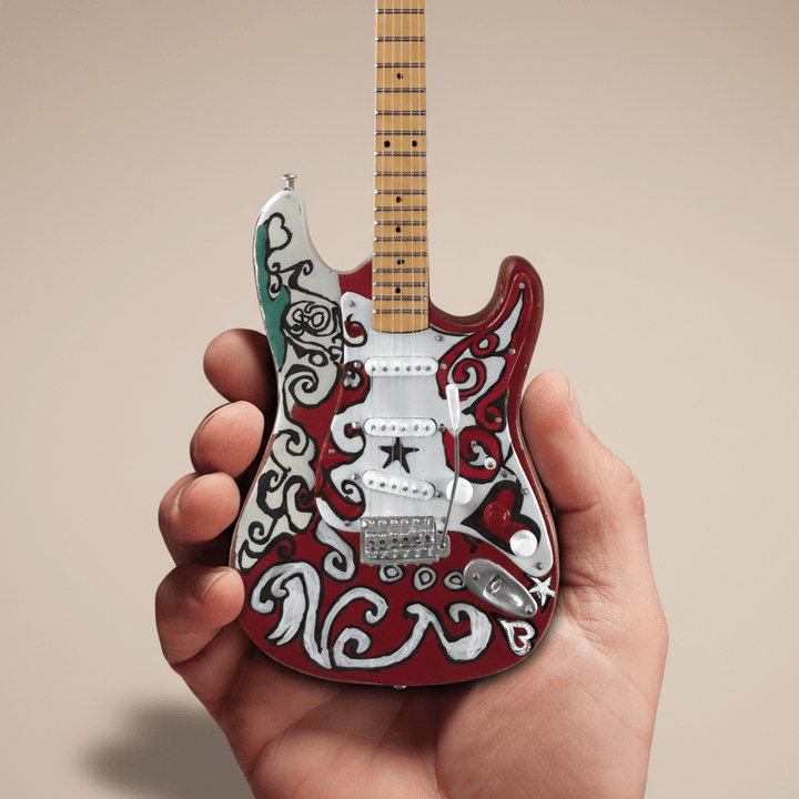 Hand holding Jimi Hendrix Fender Stratocaster Mini Guitar Replica with intricate design.