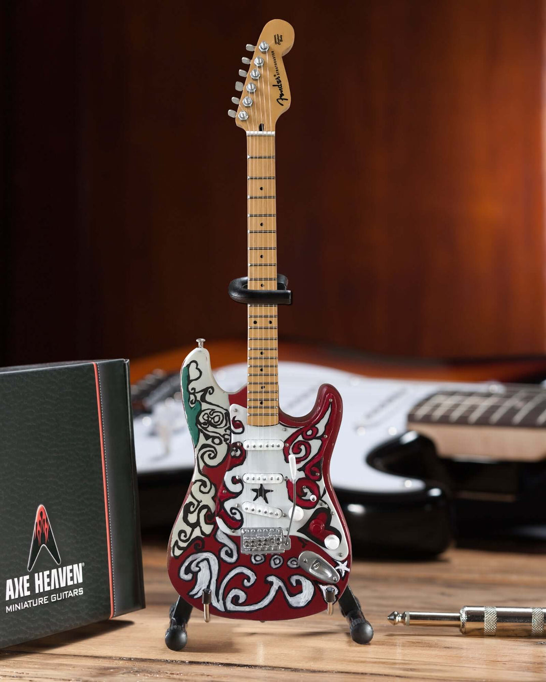 Jimi Hendrix Fender Stratocaster Mini Guitar Replica displayed on a wooden table with a vibrant background.