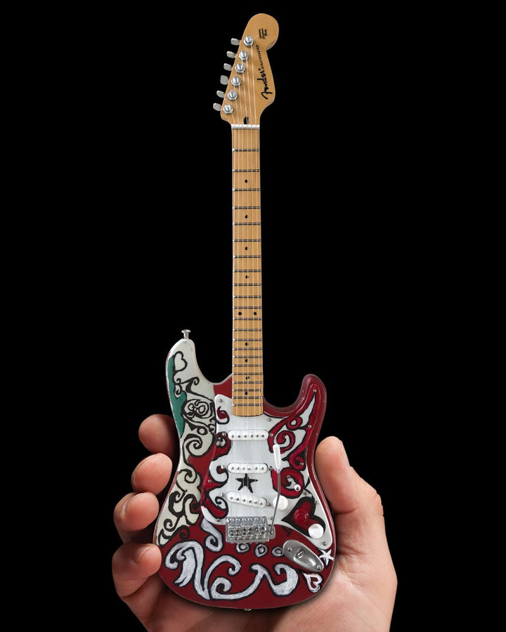 Hand holding Jimi Hendrix Fender Stratocaster Mini Guitar Replica showcasing intricate designs under studio lights.