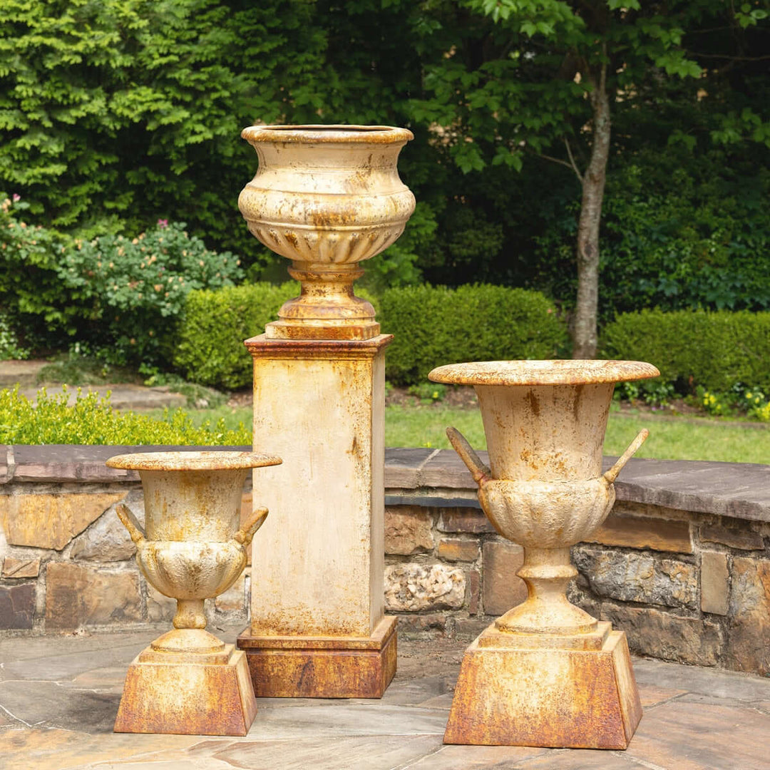 Large Rustic Metal Garden Urn with Aged Patina Finish displayed in a lush garden setting.