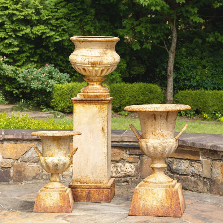 Large Rustic Metal Garden Urn with Aged Patina Finish displayed in a lush garden setting.