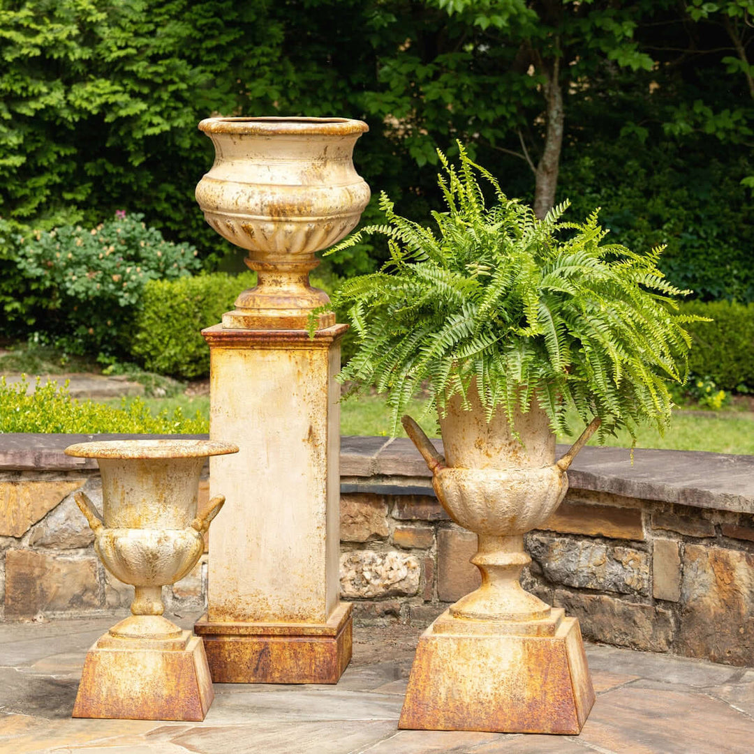 Large Rustic Metal Garden Urn with Aged Patina Finish displayed outdoors with greenery, showcasing Old World elegance.