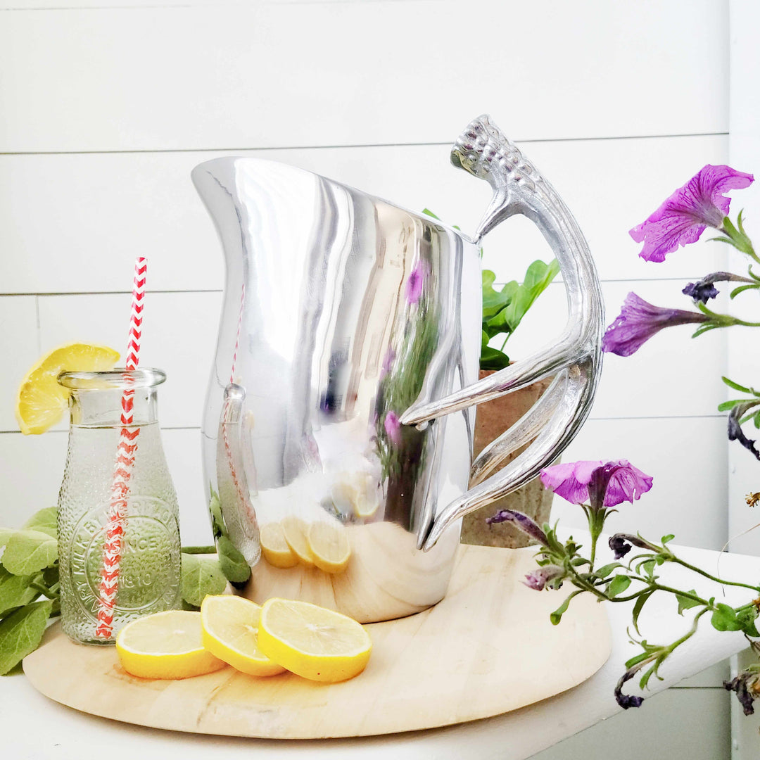 Lodge Style Antler Pitcher displayed with lemons and flowers on a wooden base, showcasing its sculptural design and majestic charm.