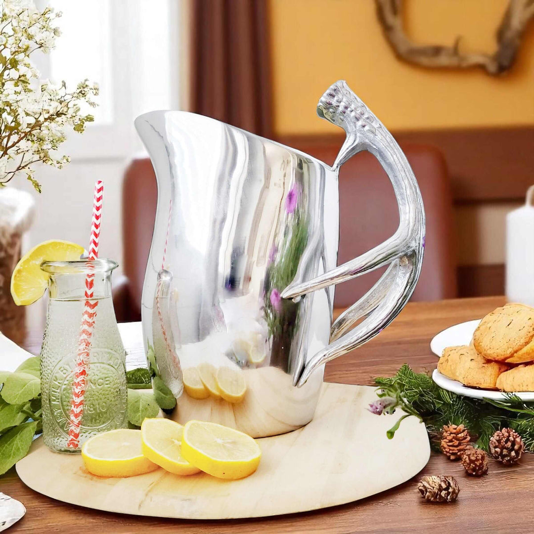 Lodge Style Antler Pitcher on wooden table with lemons and cookies, showcasing its sculptural design and intricate handle.