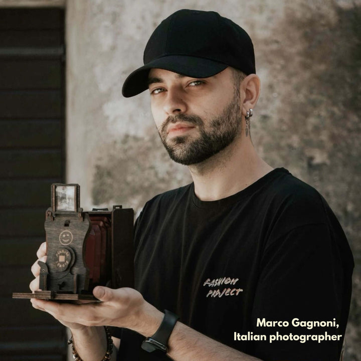 Person holding a vintage pinhole square instant film camera DIY kit outdoors