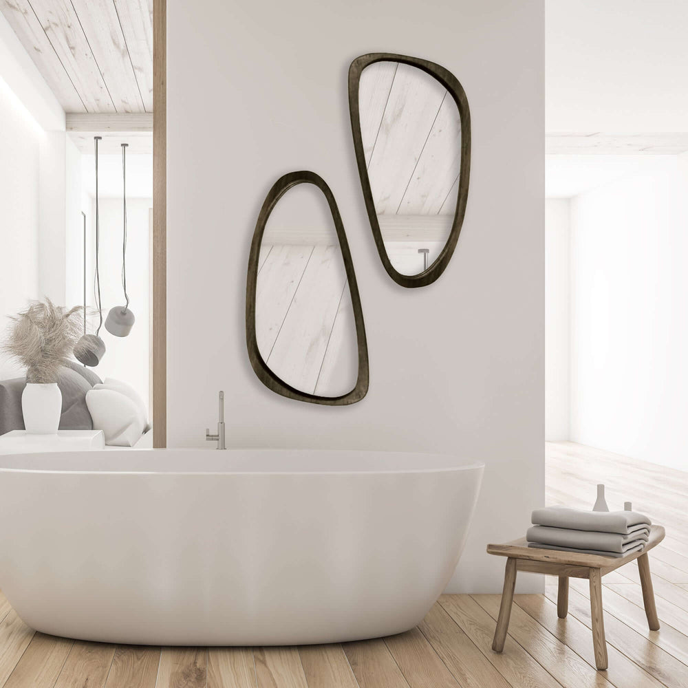 Mid-century modern asymmetrical black wood mirrors above a freestanding bathtub in a bright bathroom.