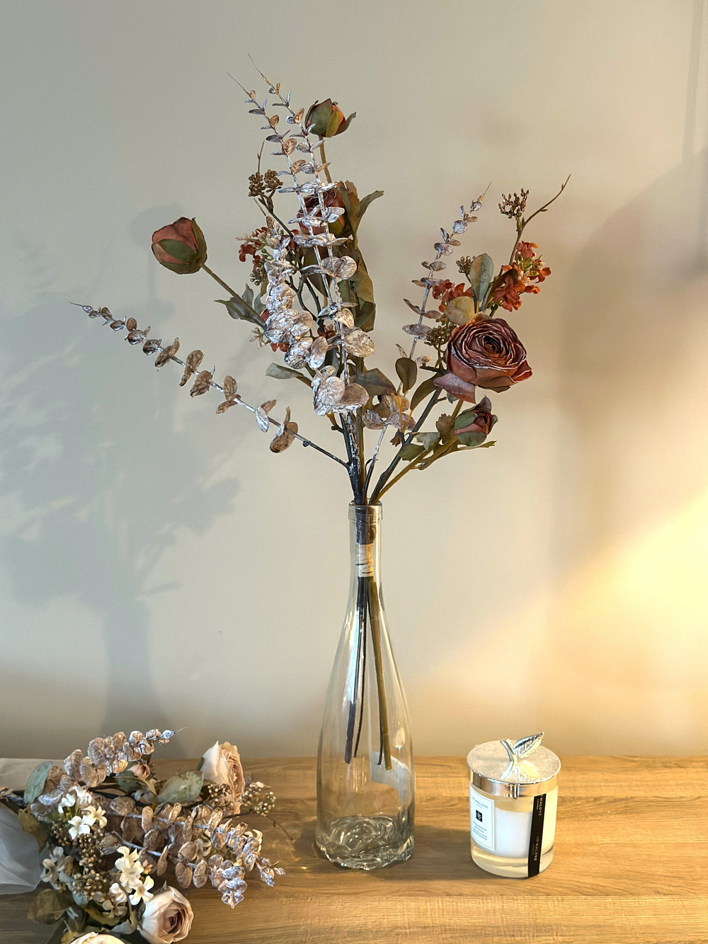 Airy faux flower bouquet with rust, white, and lavender blooms in a tall glass vase