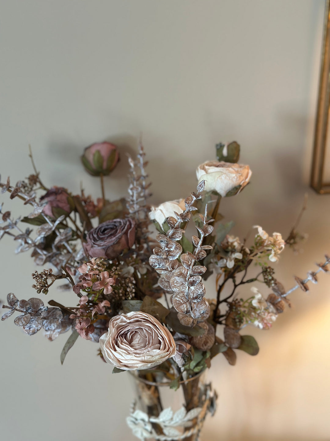 Close view of muted rose-like flowers and silvery foliage in the bouquet