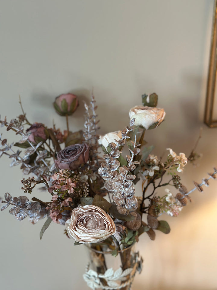 Close view of muted rose-like flowers and silvery foliage in the bouquet