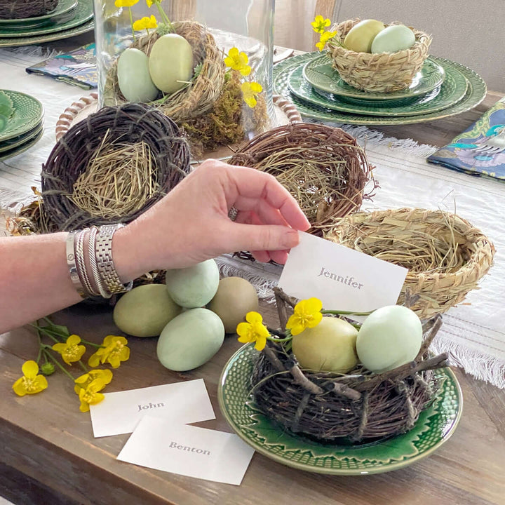 Natural rattan, grass, and bamboo bird nests used in a table setting with decorative eggs and place cards for a seasonal display.
