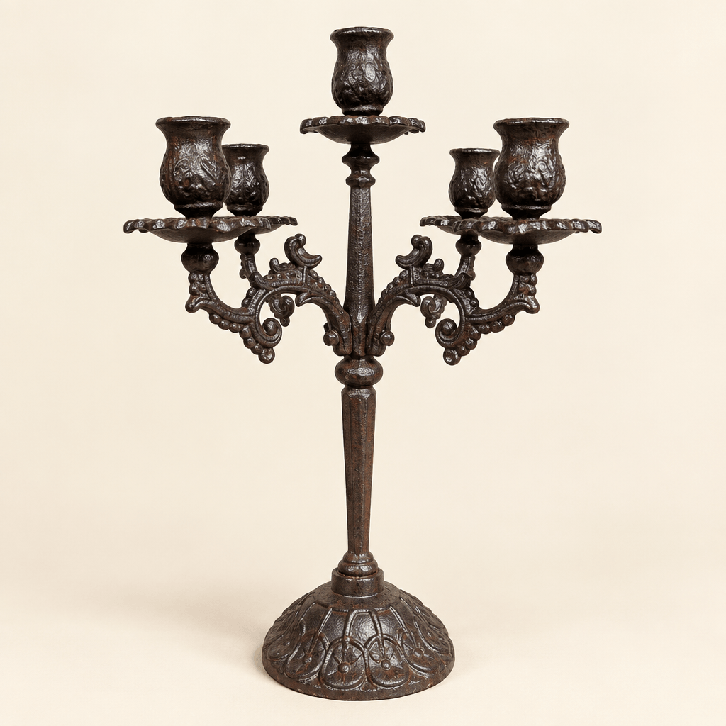 Ornate dark cast iron candelabra with five candle cups on a warm ivory studio background