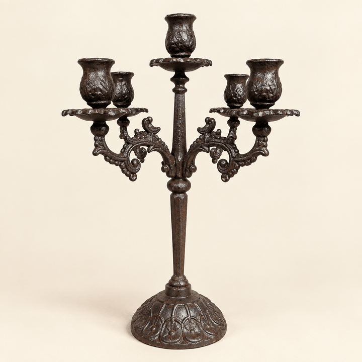 Ornate dark cast iron candelabra with five candle cups on a warm ivory studio background