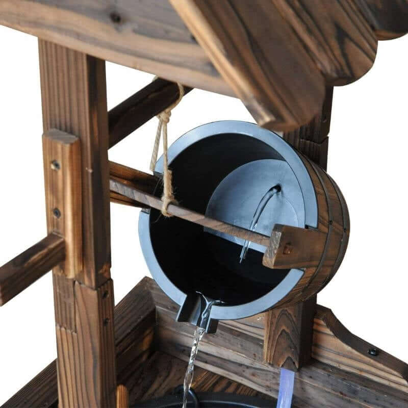 Close-up of Outdoor Garden Wishing Well Water Fountain with water flowing from a wooden bucket into the well basin.