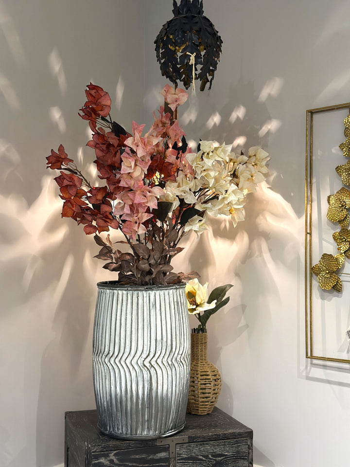 White, pink, and red bougainvillea faux flower stems arranged in a tall ribbed vase