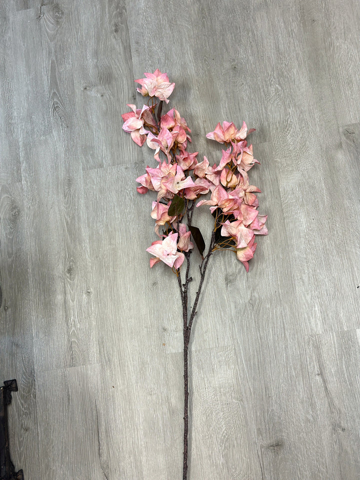 Pink bougainvillea faux flower stem laid flat with soft green leaves