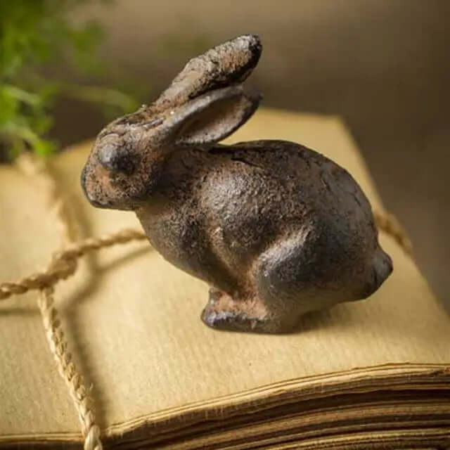 Small aged cast iron rabbit resting on a twine-tied book