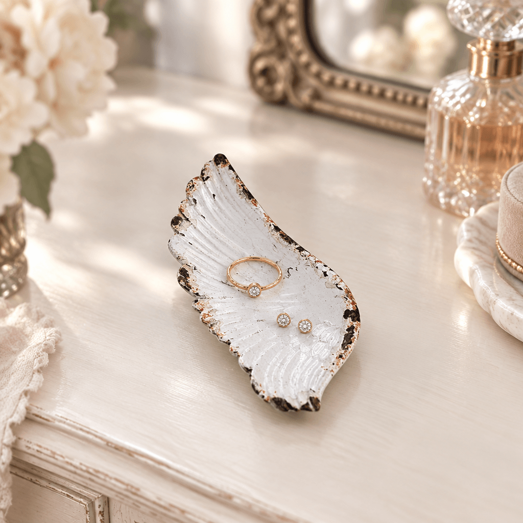 Rustic white pewter angel wing jewelry tray styled with a ring and earrings on a vanity