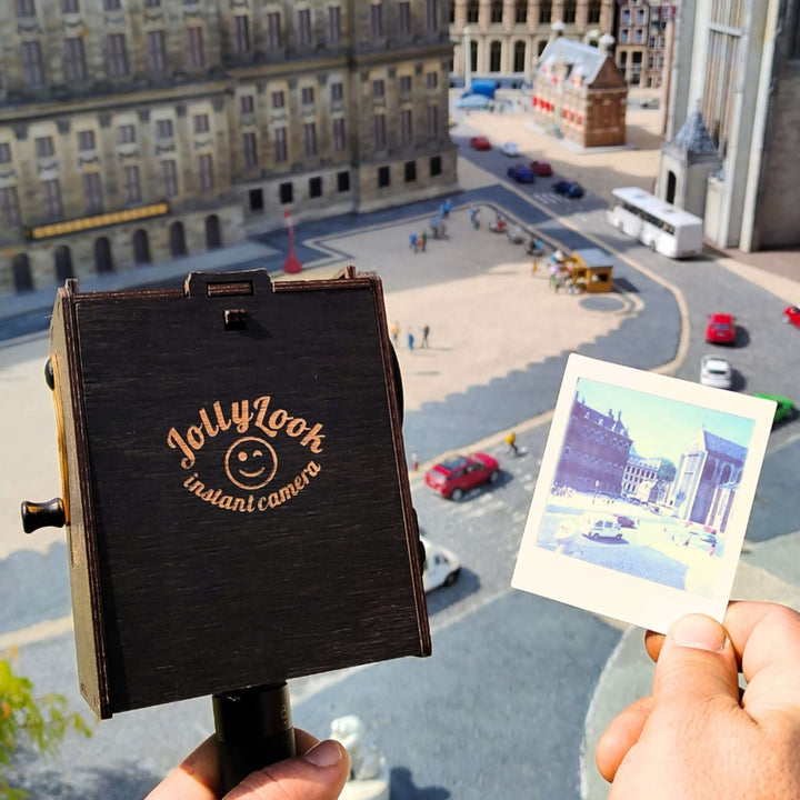 Person using Pinhole Square Instant Film Camera DIY Kit to take a vintage-inspired photo in a city square setting.