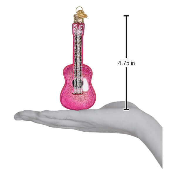 Pink Glitter Guitar Christmas Ornament with sparkling pink design shown in hand for scale, measuring 4.75 inches tall.