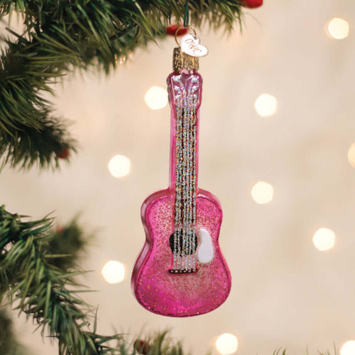 Pink Glitter Guitar Christmas Ornament hanging on tree, sparkling with lights, celebrating music and joy with vibrant style.