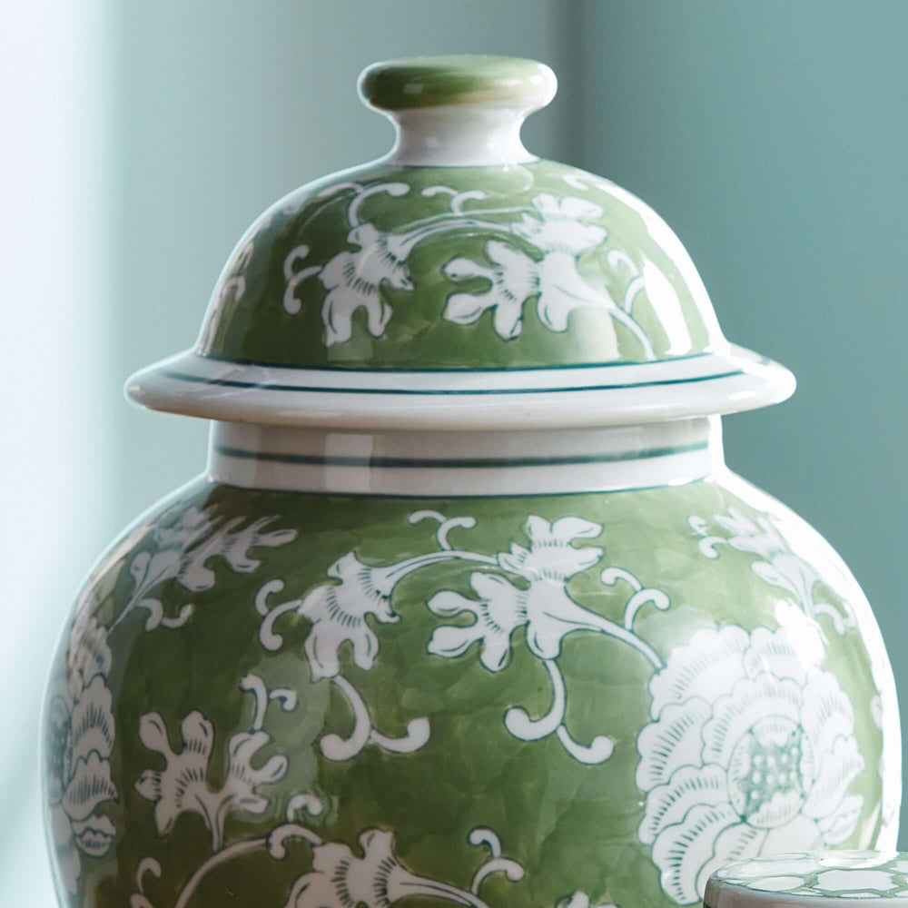 Porcelain green chinoiserie lotus ginger jar with lid, featuring intricate white floral patterns on a green background.