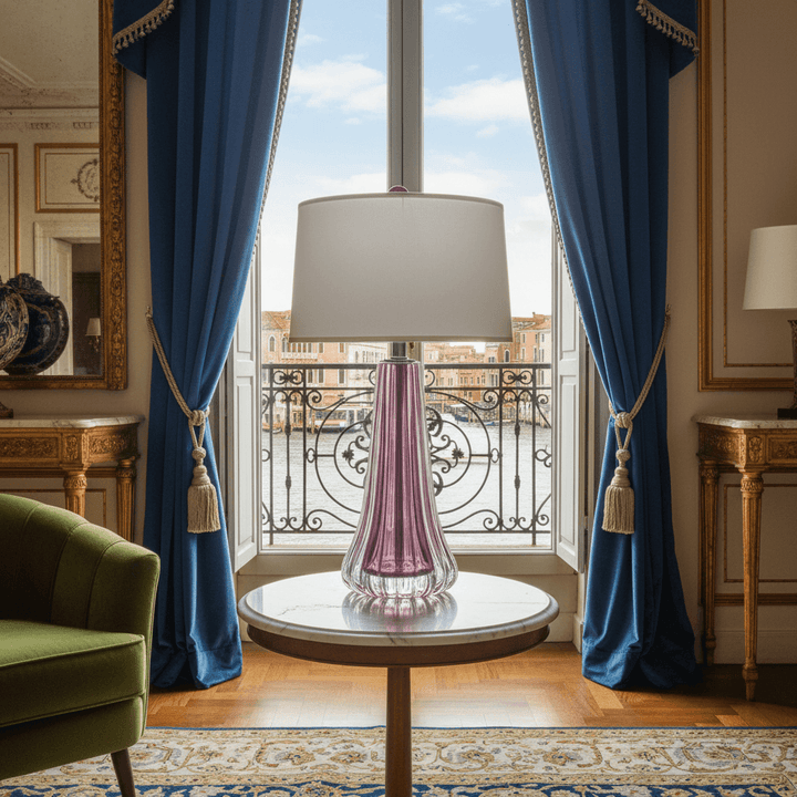 Luxurious room with a purple glass lamp on a table by a large window with blue curtains. Venice, Italy is in the background.