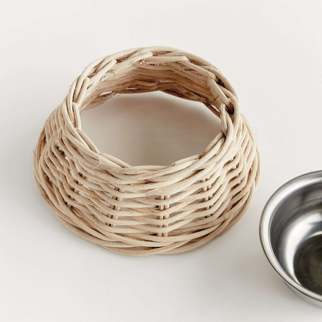 Rattan Pet Bowl with Stainless Steel Insert on wooden floor, showcasing handwoven rustic design for home décor pet dining.