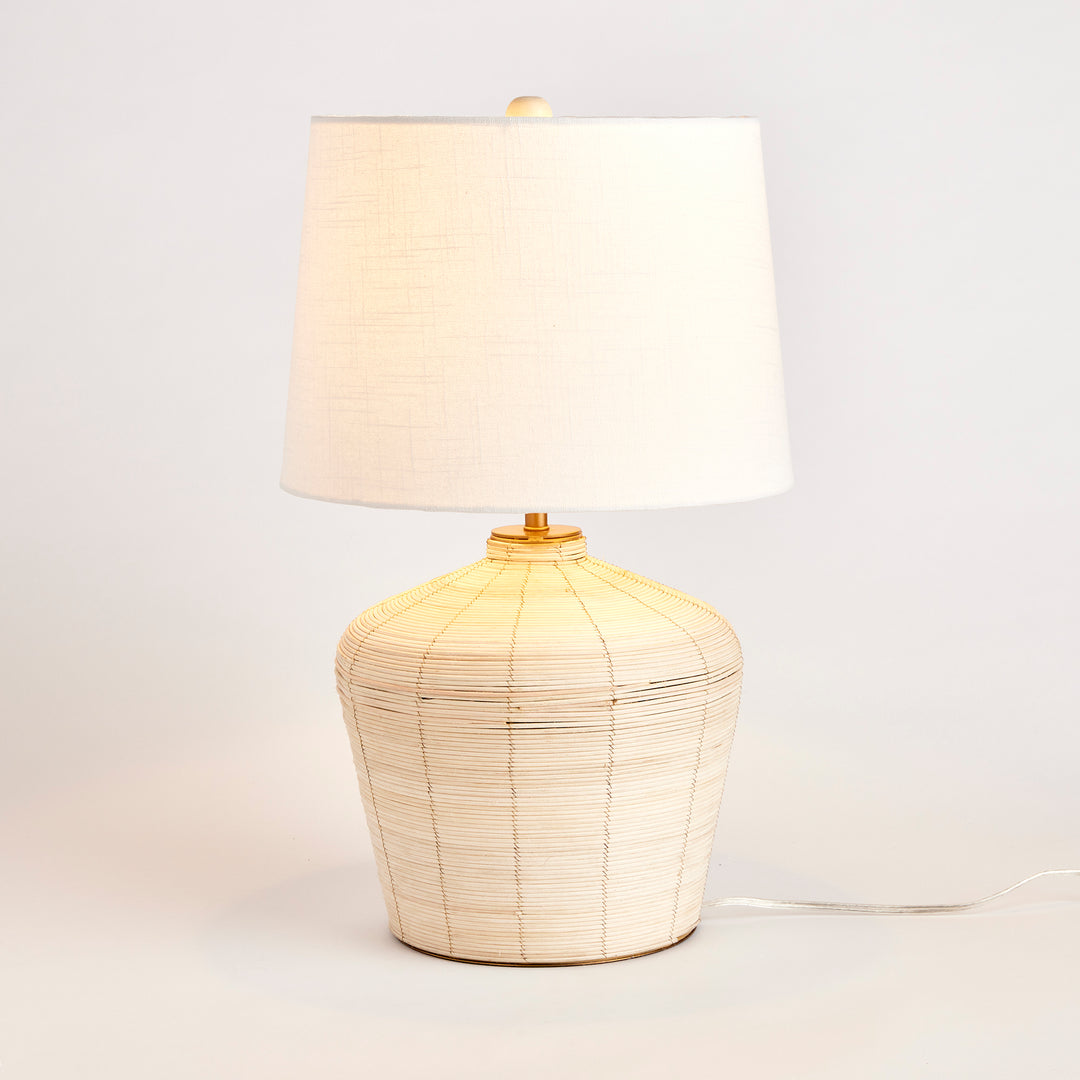 Rattan table lamp with curved base and white shade, showcasing organic elegance and coastal design.