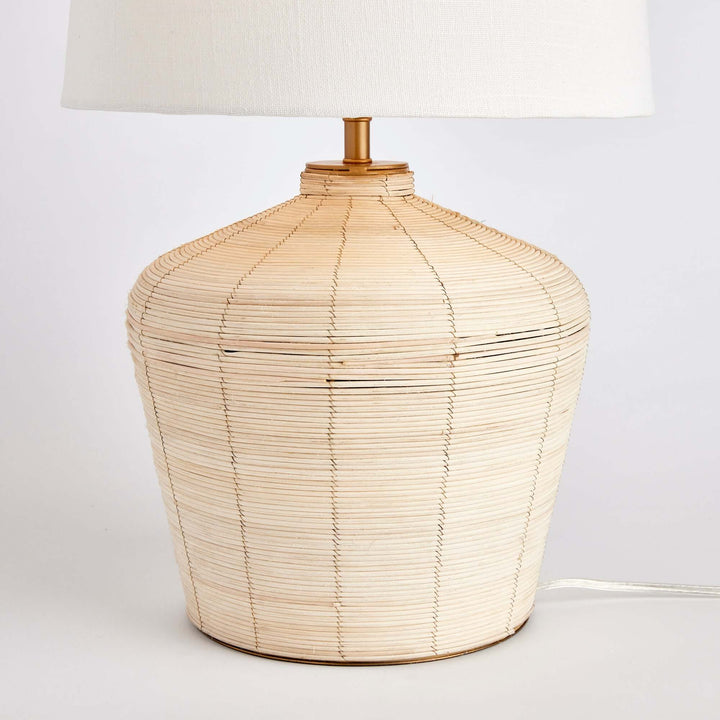 Rattan table lamp with curved base and white shade, showcasing handwoven detail and organic elegance.