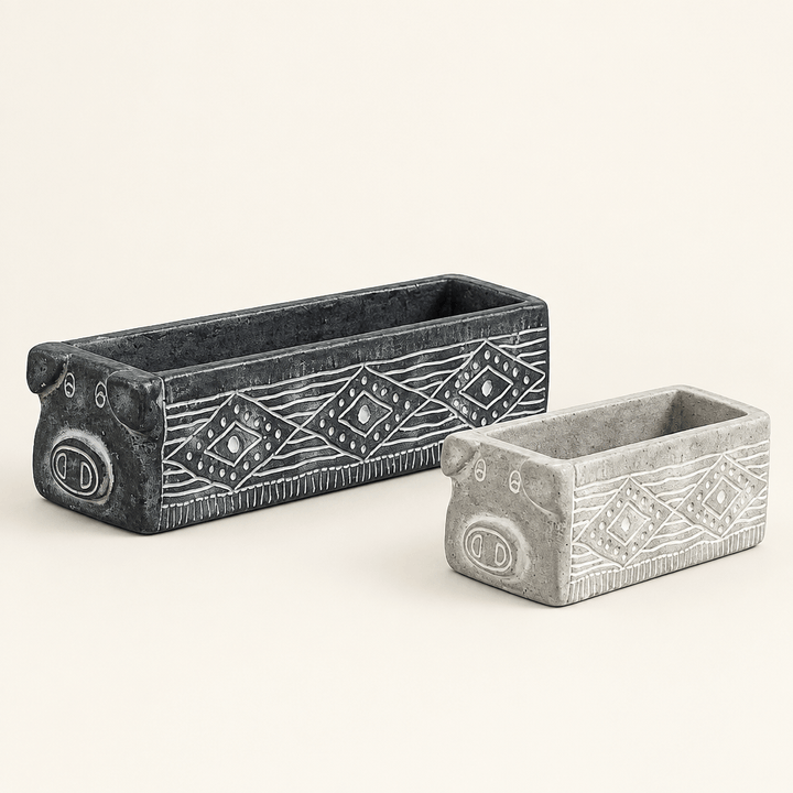 Large black and small gray rectangular cement pig planters with pale geometric details on an ivory background