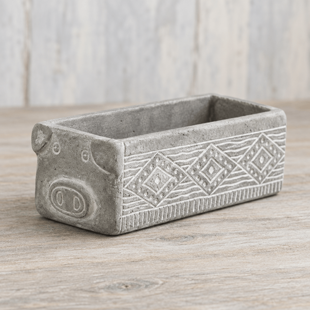 Gray cement pig planter showing its raised snout, small ears, and etched geometric side pattern