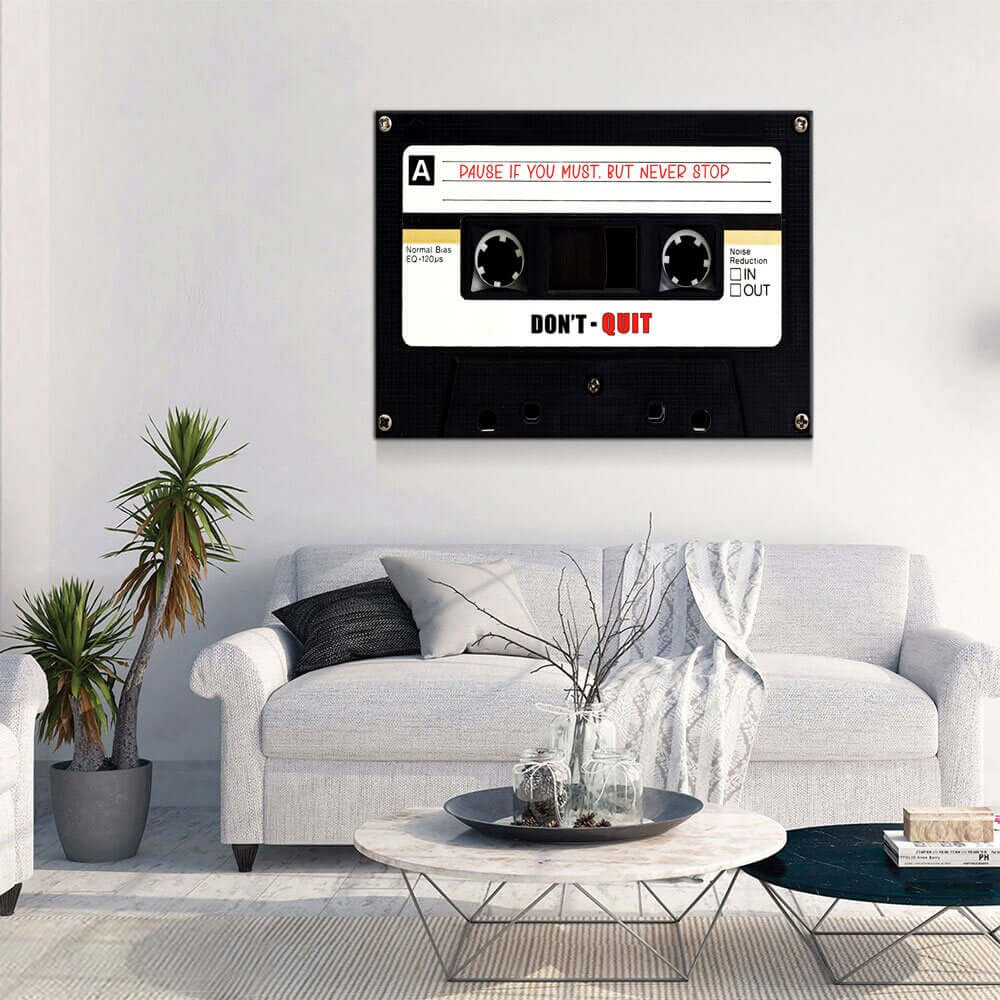 Retro Cassette Tape Motivational Wall Art hanging above a modern living room sofa with plants and a coffee table.