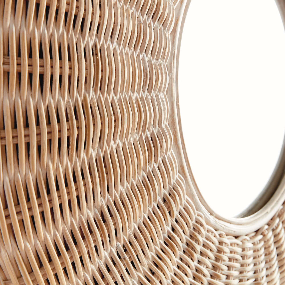Close-up of a round woven rattan wall mirror showcasing intricate, natural rattan craftsmanship and soft radial patterns.