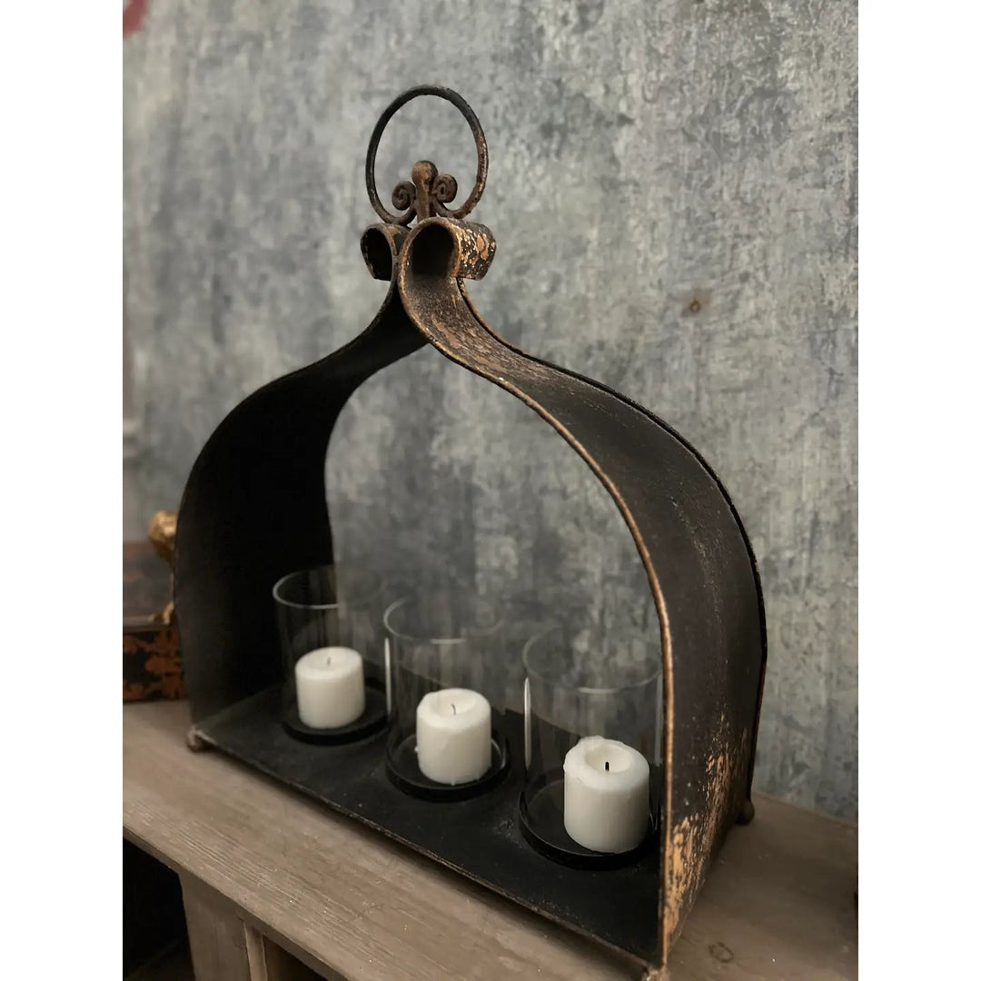 Cast iron triple candle holder styled near a stone hearth