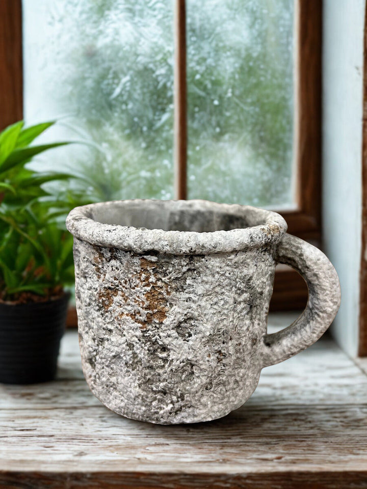 Weathered cement mug planter styled with garden tools