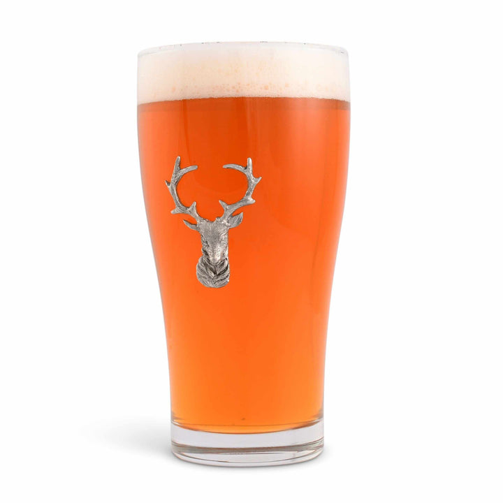 Pint glass with a deer head emblem filled with orange beer on a white background
