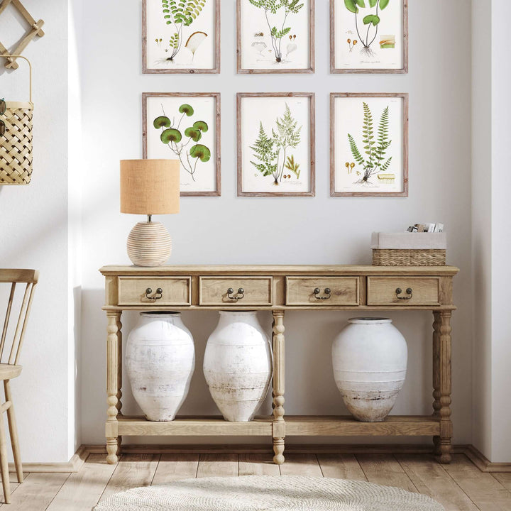 Rustic mango wood table lamp with linen shade on a console table, surrounded by antique pots and botanical art.