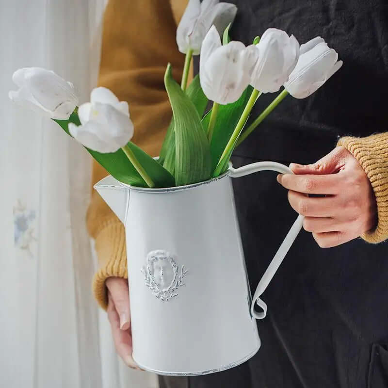 Large white metal flower pitcher vase held with tulips