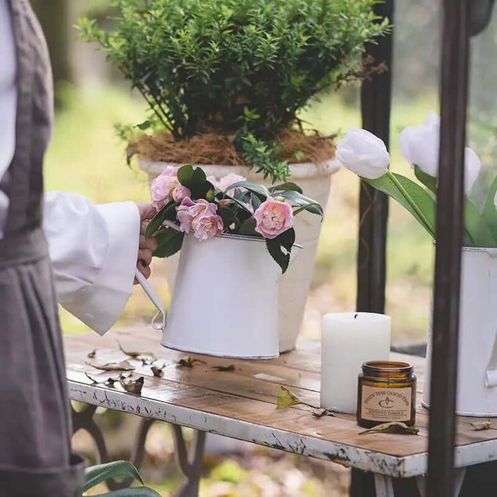 Small rustic white metal pitcher vase styled on a table
