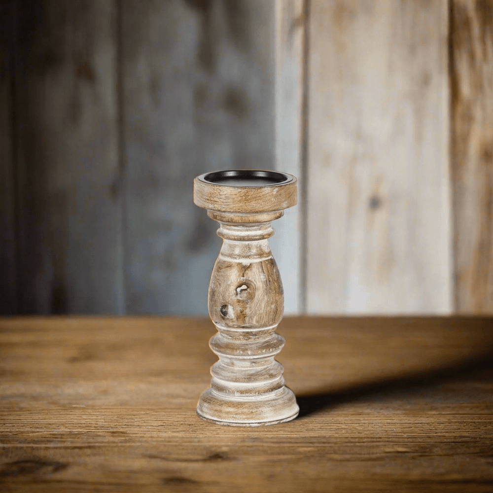 Rustic whitewashed mango wood pillar candle holder on wooden table, showcasing hand-carved design and natural grain pattern.