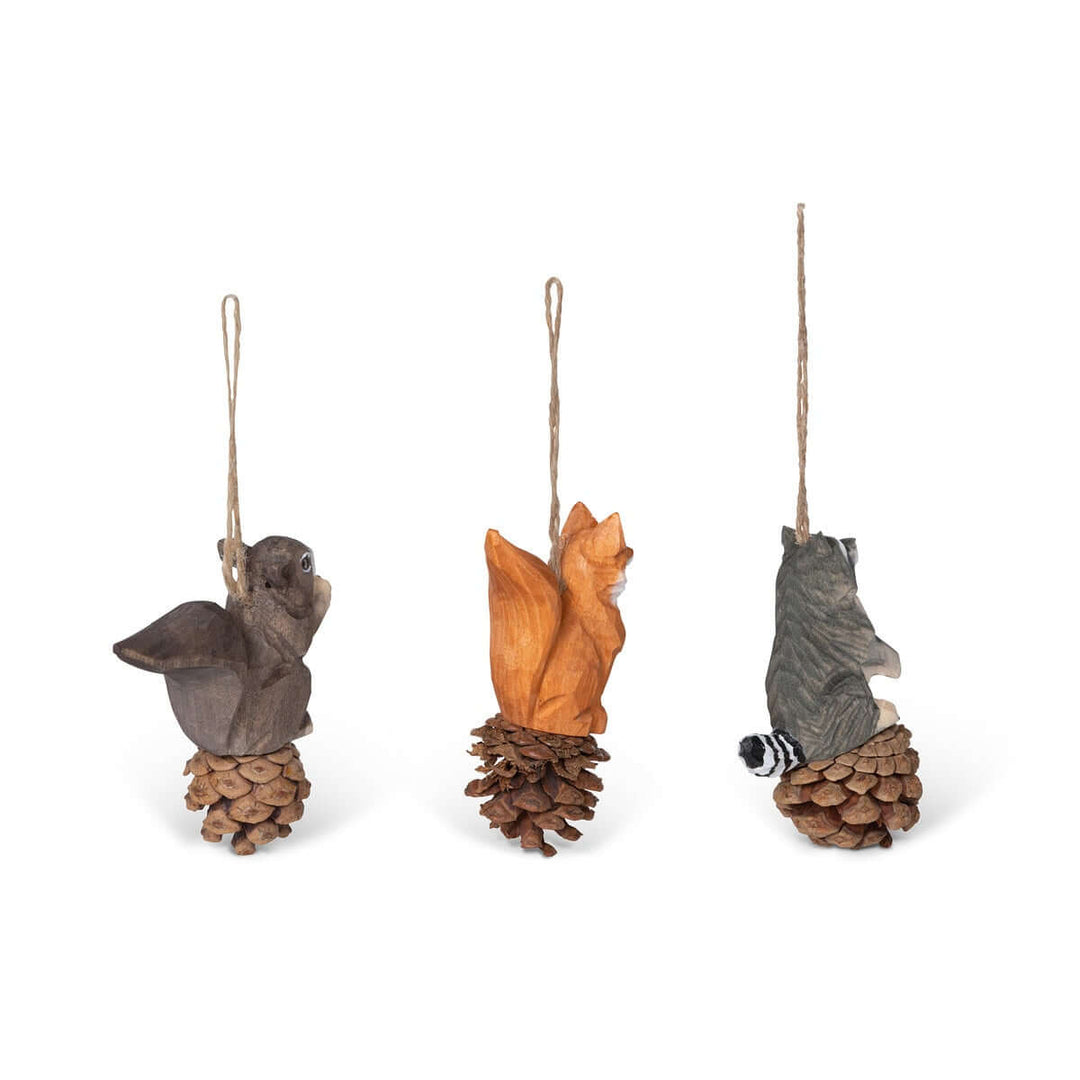 Set of 3 rustic woodland animal ornaments featuring squirrel, fox, and raccoon, hand-carved from wood on pinecones with jute strings.