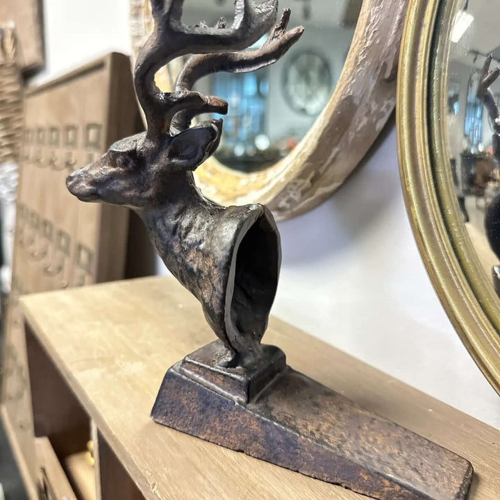 Rustic cast iron deer door stopper with antlers on a wooden shelf, reflecting woodland charm and vintage design.