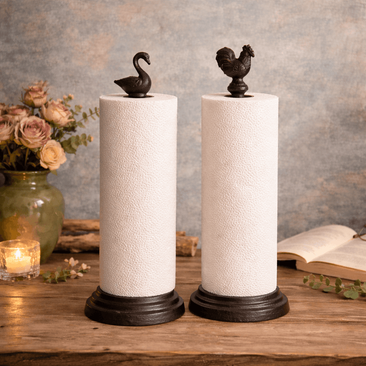 Rustic Cast Iron Rooster Paper Towel Holder with Weighted Base displayed on a wooden table with vintage decor.