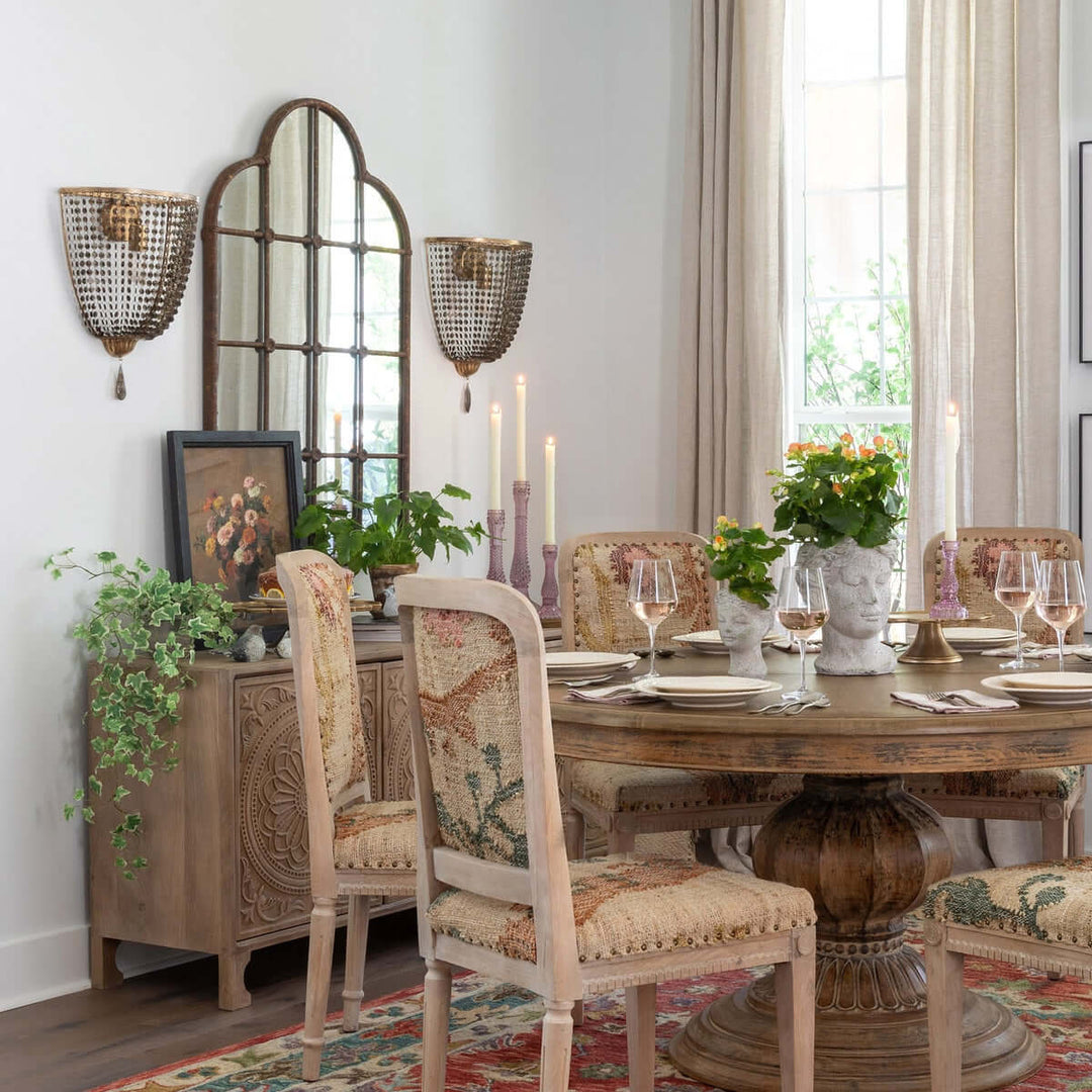 Dining room with Rustic Farmhouse Iron Windowpane Mirror, wooden table, upholstered chairs, green plants, and wall sconces.