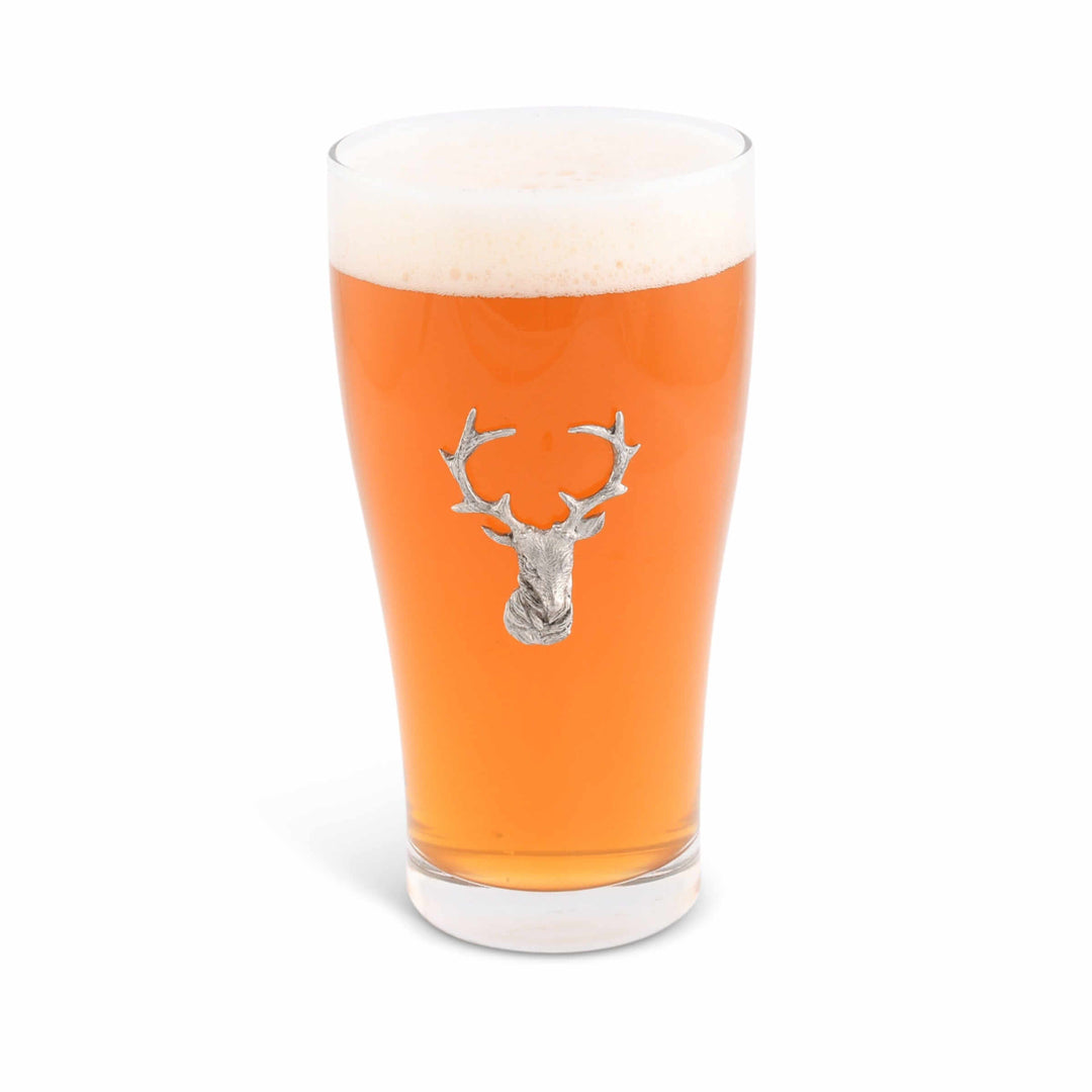 Pint glass with a deer head emblem filled with orange beer on a white background