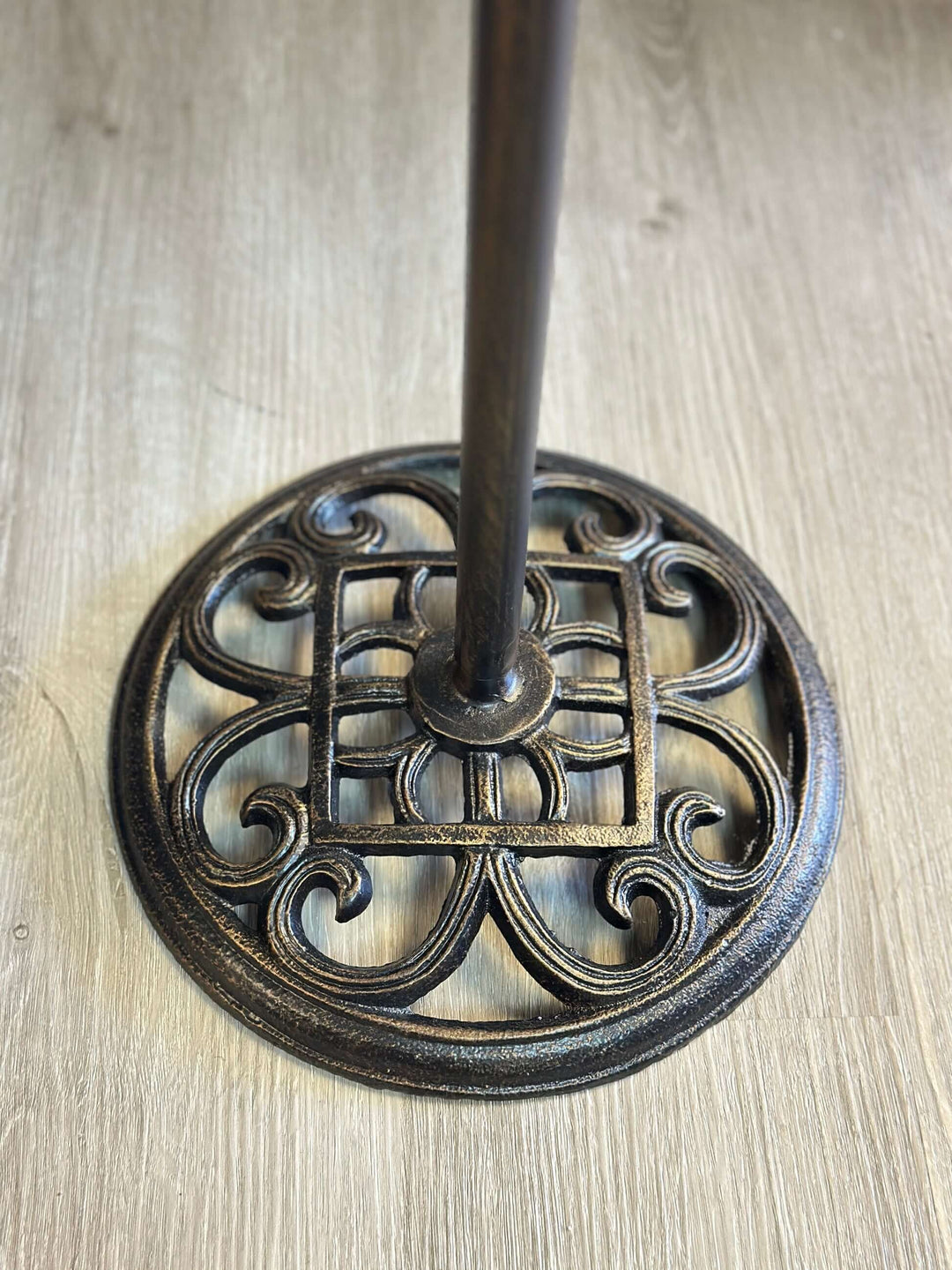 Ornate rustic bronze base of farmhouse metal chalkboard stand with twisted rod design.