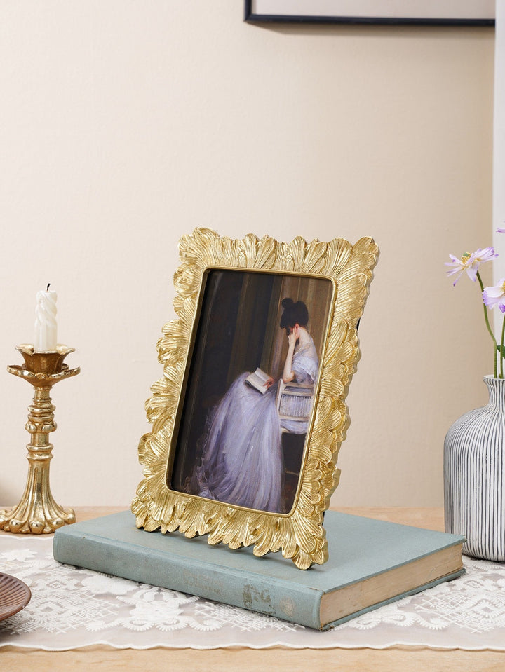 Gold Sculpted Leaf Photo Frame for a 5 by 7 photograph on a book