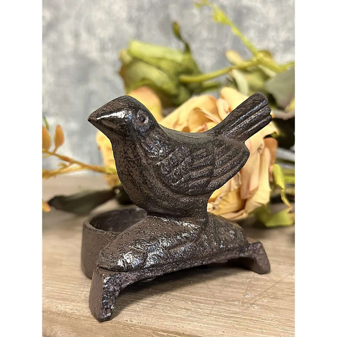 Three-quarter view of the textured metal bird candle stand with dark rubbed finish